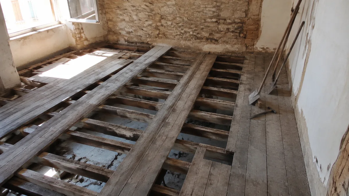 Plancher bois ancien visible au droit d'un mur mitoyen dans un immeuble marseillais